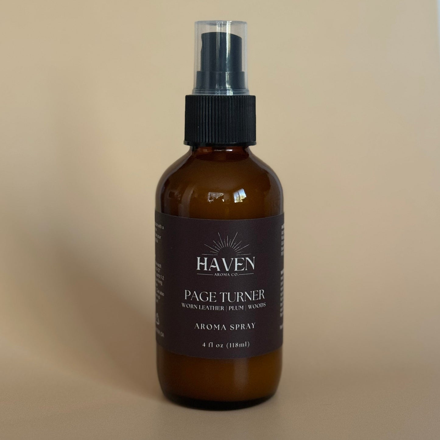 Amber aroma spray bottle with black label on a beige background