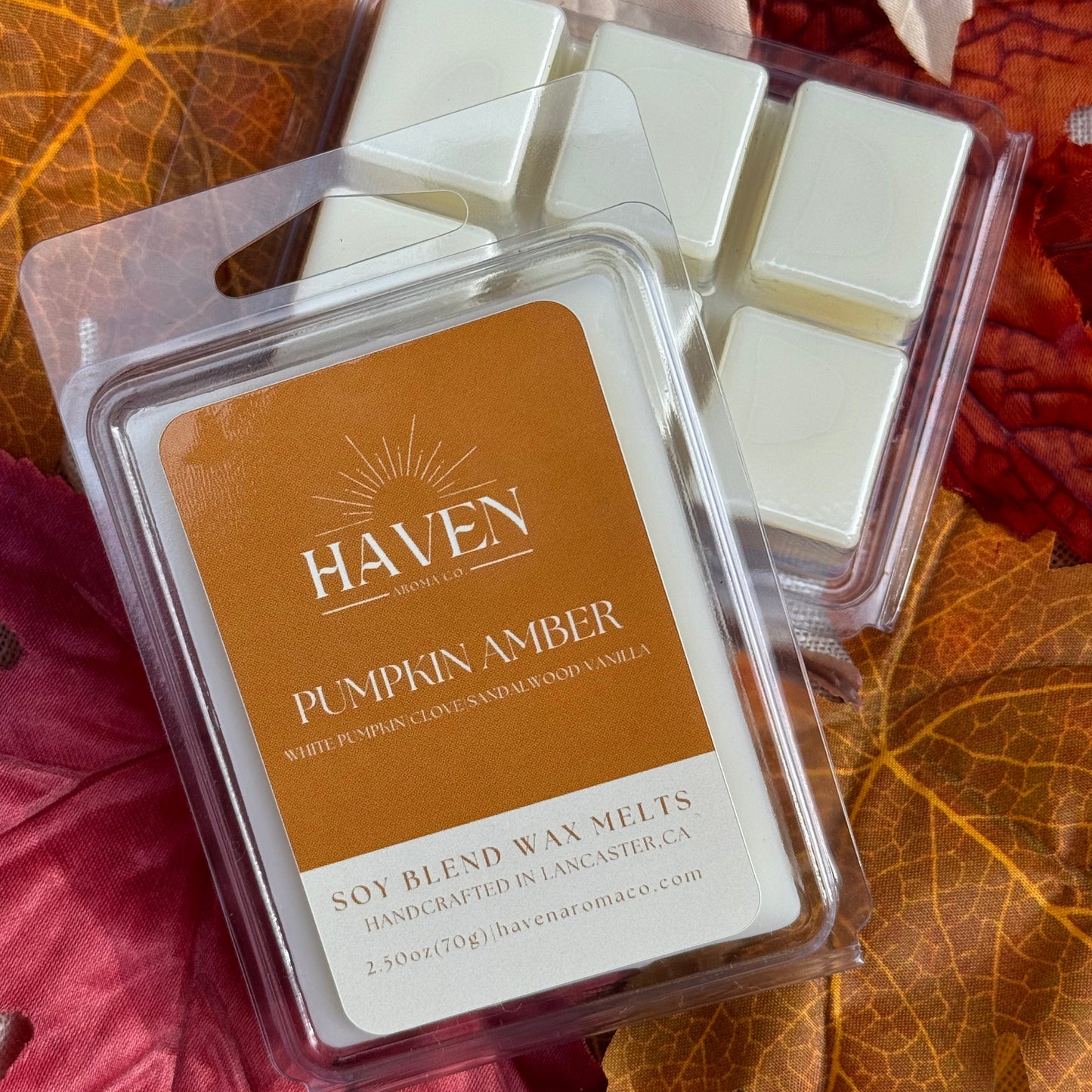 Packaged Pumpkin Amber wax melt cubes with 'HAVEN' branding on the label, displayed on a background with autumn leaves.